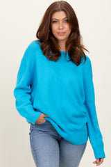 woman wearing a bright turquoise oversized sweater with a crew neckline and relaxed fit, paired with denim jeans