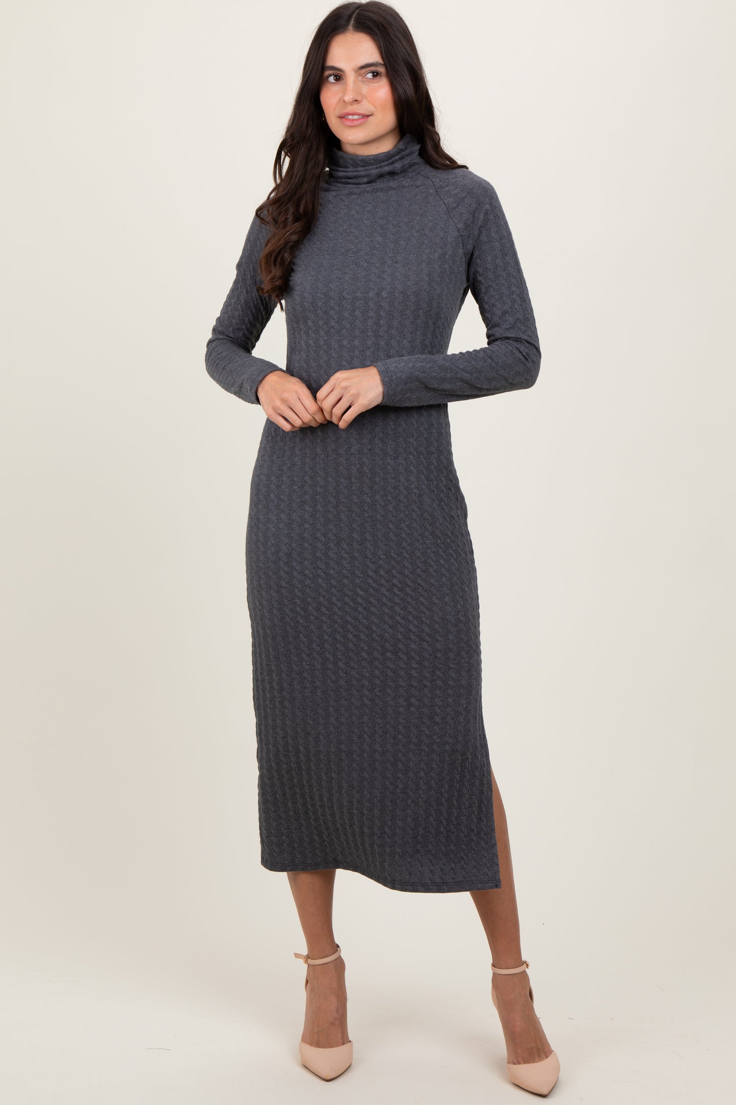 woman wearing a dark grey long sleeve turtleneck midi dress with textured pattern and side slit