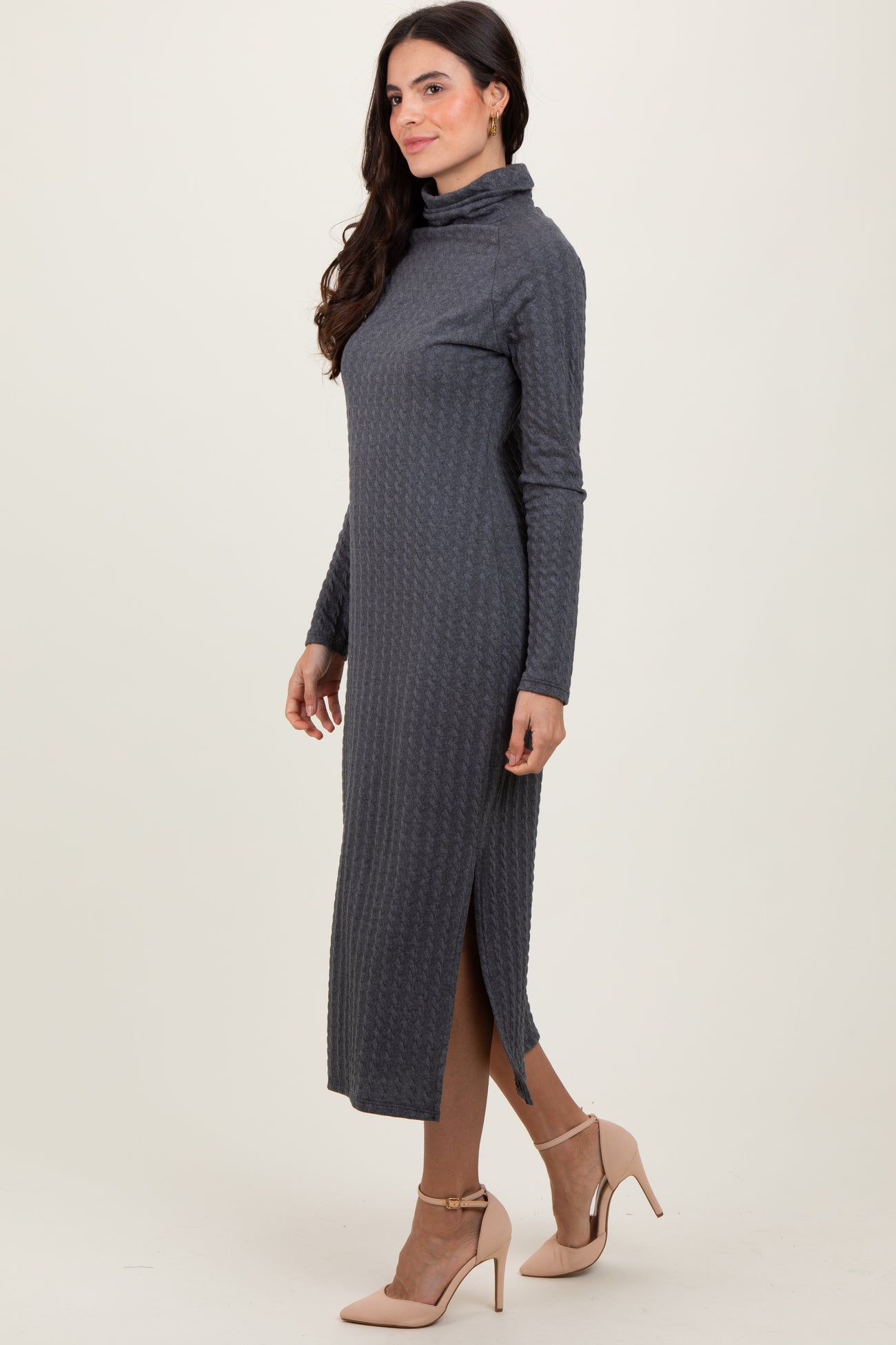 woman wearing a dark gray long sleeve midi dress with a turtle neck and side slit, styled with beige high heels