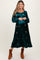woman wearing a green floral velvet maternity dress with long sleeves and a baby bump