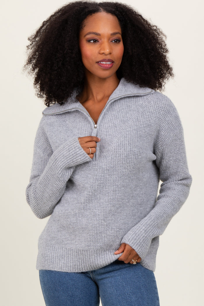 woman wearing a light grey zip-up sweater with a relaxed fit and ribbed detailing, posing confidently
