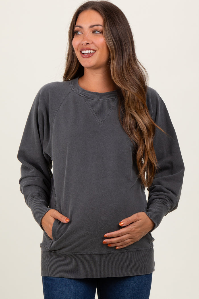 woman wearing a charcoal gray maternity sweatshirt with a relaxed fit and pockets, holding her baby bump