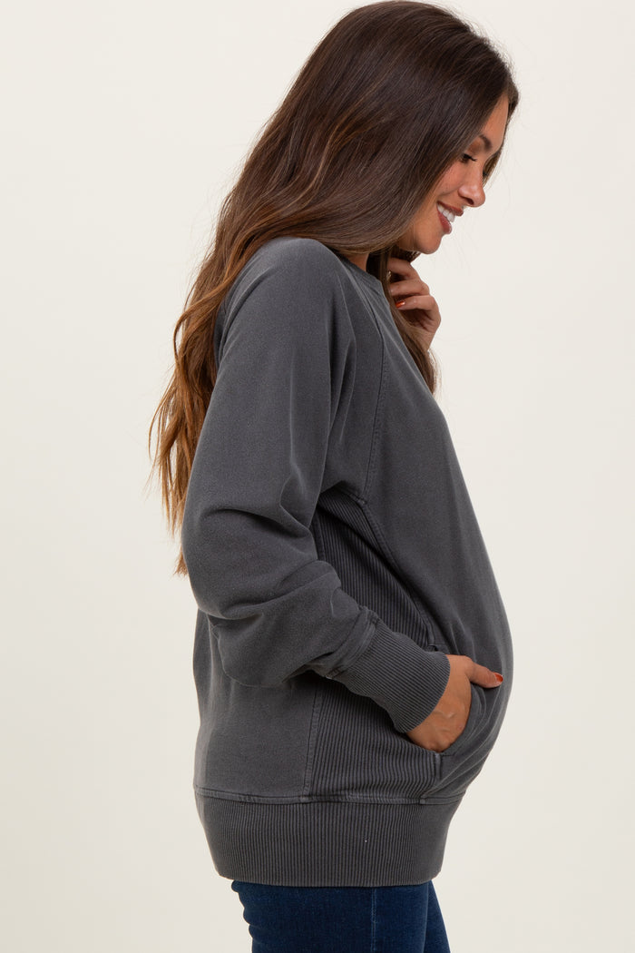woman wearing a gray maternity sweatshirt with side pockets and ribbed detailing, showing her baby bump