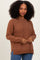 woman wearing a brown long sleeve sweater with raglan sleeves and side slits, styled with blue jeans