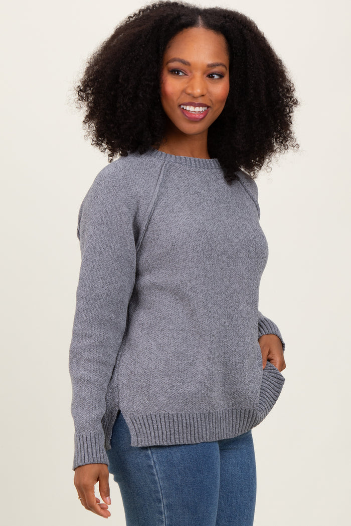 woman wearing a gray knit sweater with side slits and raglan sleeves, paired with blue jeans