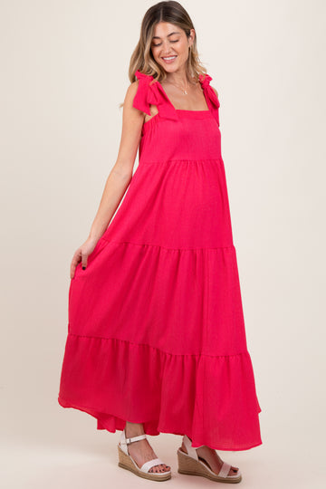 woman wearing a bright pink tiered maternity dress with bow straps and a visible baby bump