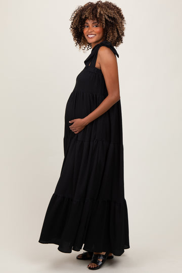 woman wearing a black tiered maxi dress with tie straps, showing off her baby bump