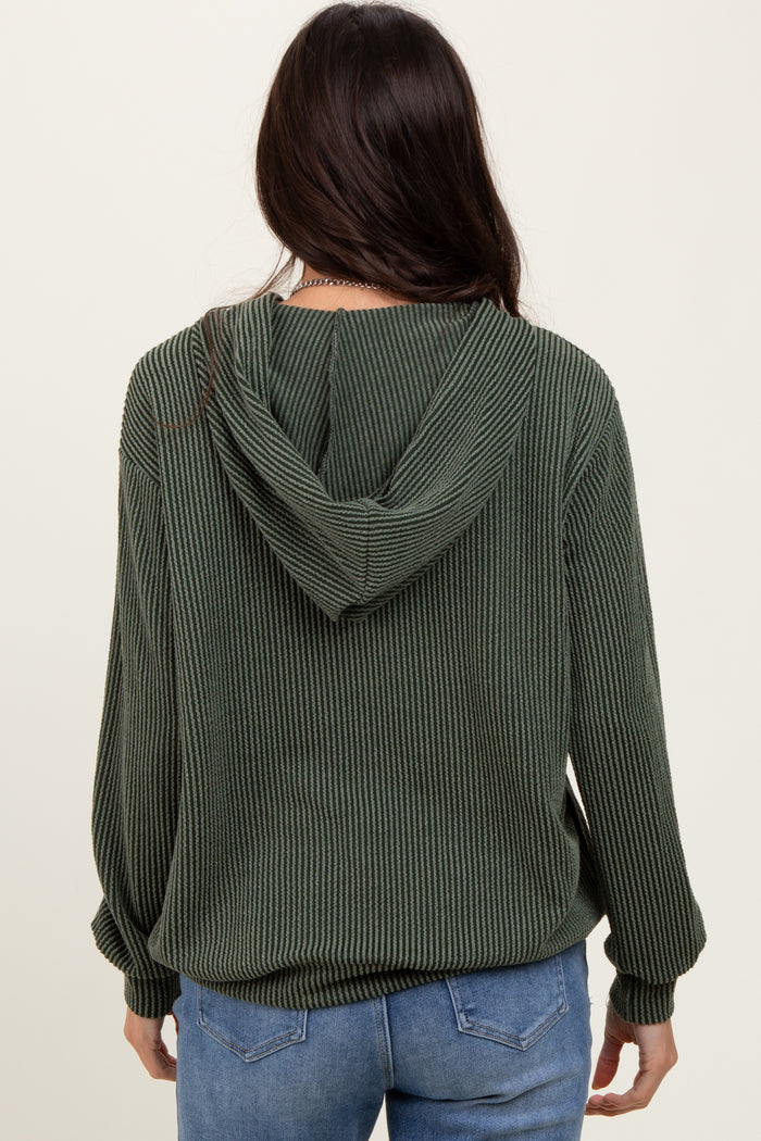 woman wearing a green ribbed hooded sweatshirt, facing away, paired with blue jeans