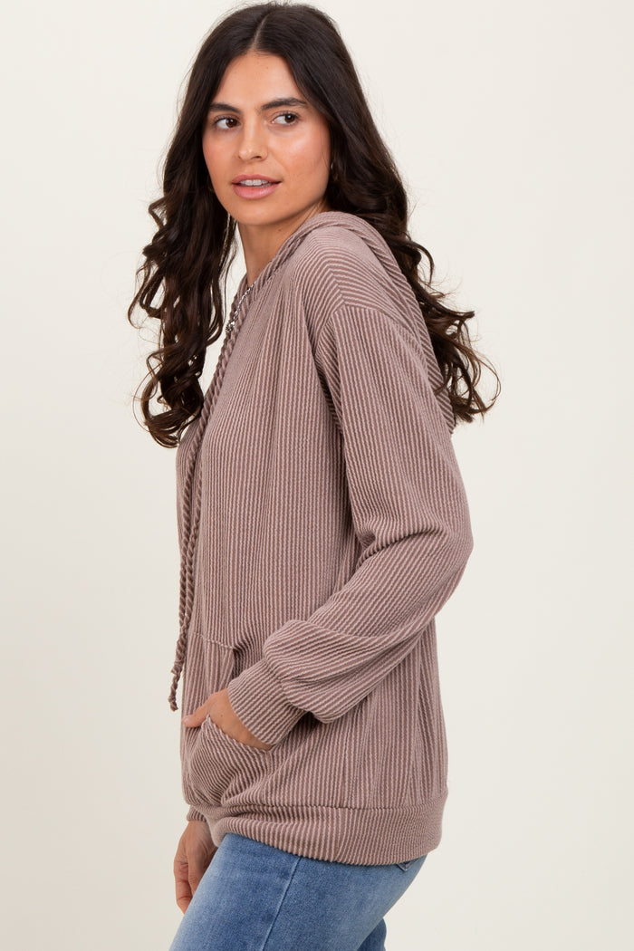 woman wearing a beige ribbed hooded sweatshirt with a front pocket and drawstring detail, styled with blue jeans