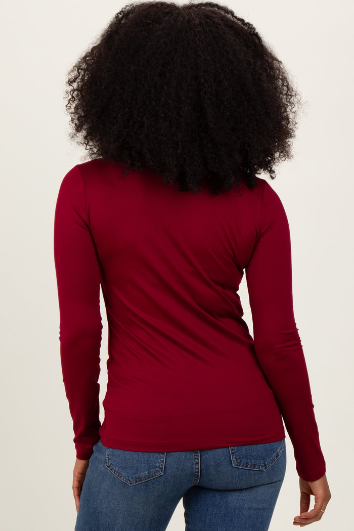 woman wearing a burgundy long sleeve top and blue skinny jeans, viewed from the back