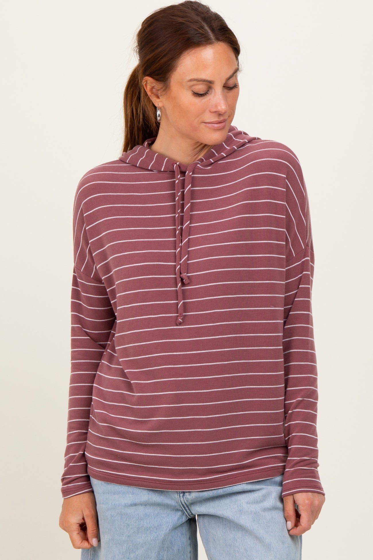 woman wearing a maroon striped pullover hoodie with a drawstring and relaxed fit