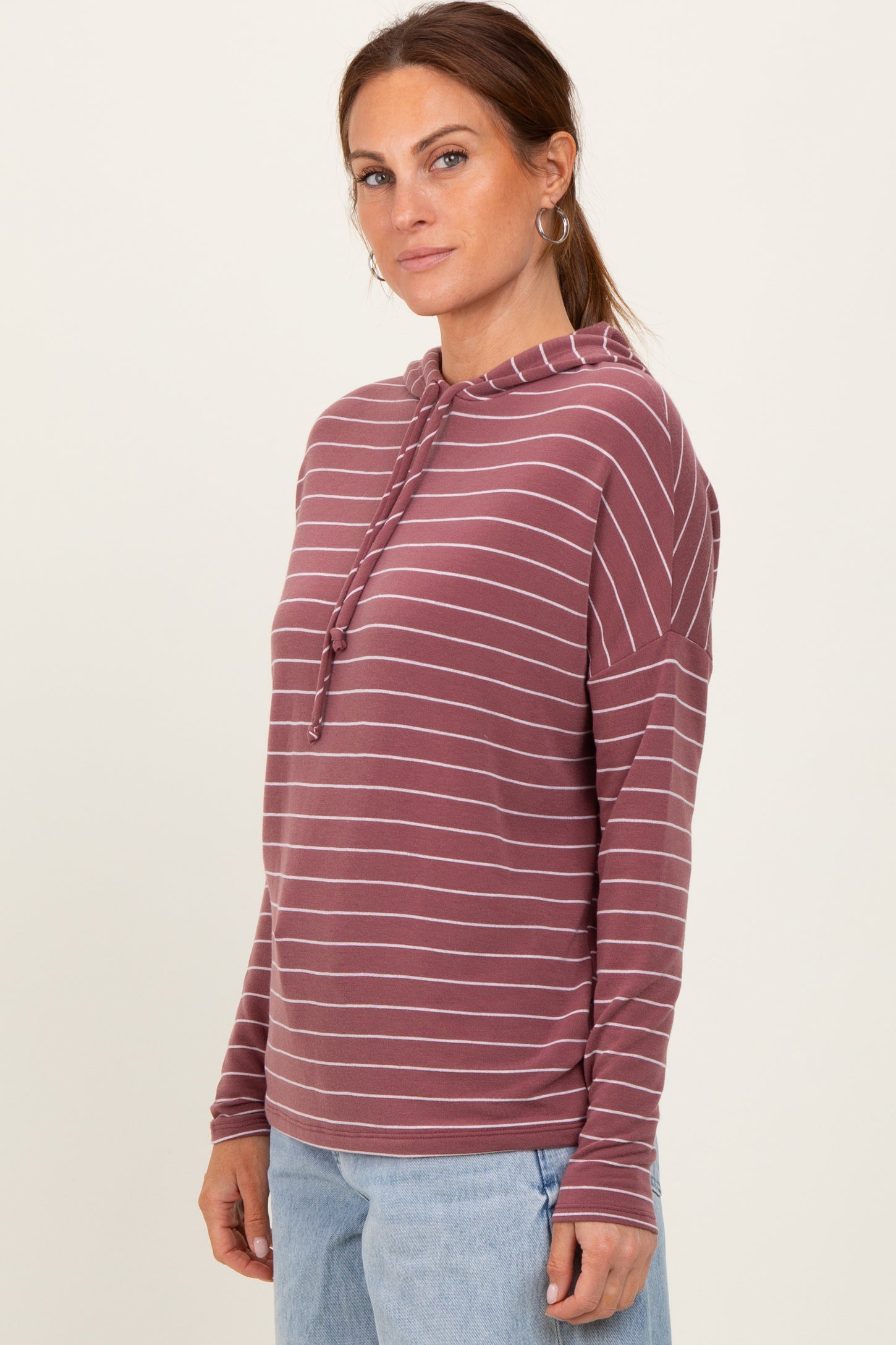 woman wearing a maroon and white striped long sleeve hoodie with a drawstring and relaxed fit