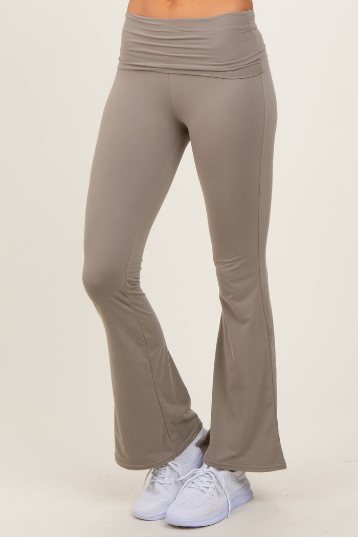 woman wearing light brown flared yoga pants paired with white athletic shoes on a beige background