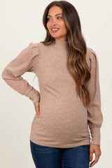 woman wearing a tan ribbed maternity sweater with puffed sleeves and a visible baby bump
