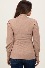 woman wearing a ribbed beige maternity sweater with a high neck and puffed sleeves, showing her back