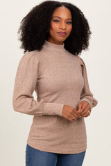 woman wearing a tan ribbed mock neck sweater with puff sleeves and long sleeves, smiling at the camera