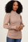 woman wearing a tan ribbed mock neck sweater with puff sleeves and long sleeves, smiling at the camera