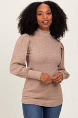 woman wearing a beige ribbed long sleeve top with puffed sleeves and a high neck, styled with blue jeans