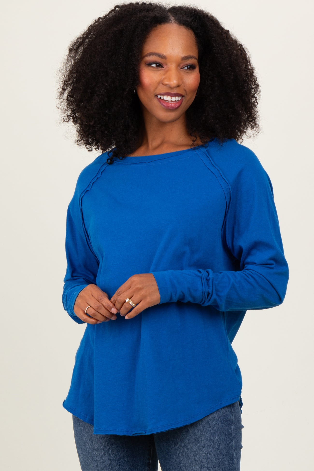 woman wearing a bright blue long sleeve top with a rounded neckline and relaxed fit, paired with jeans