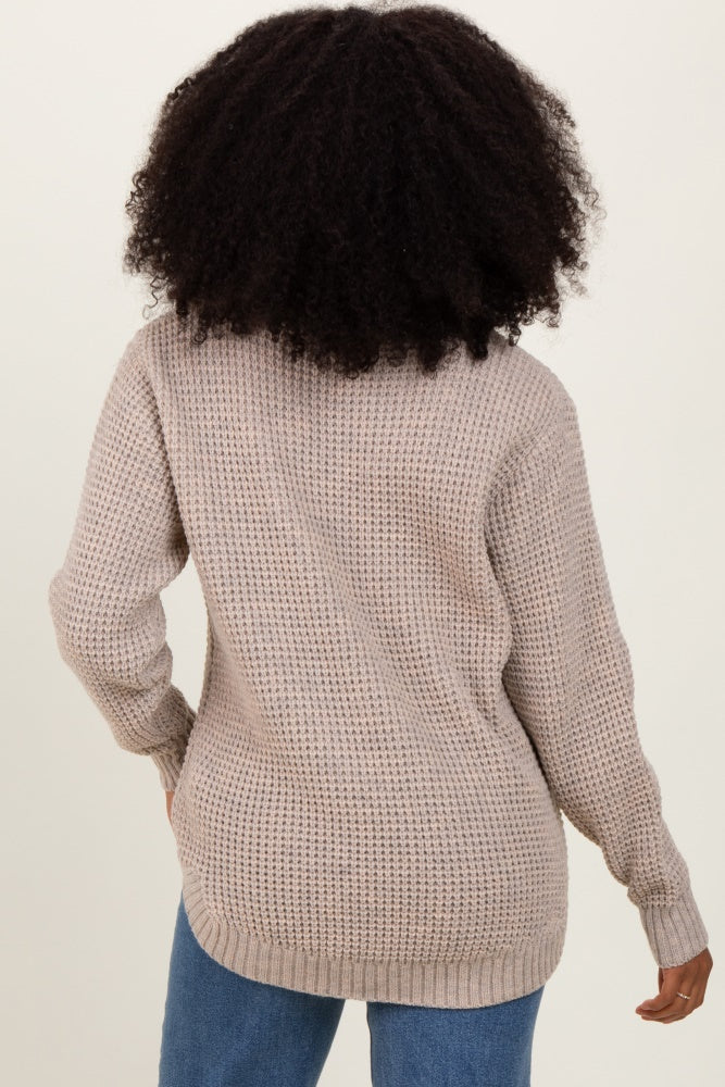 woman wearing a beige oversized knit sweater from the back, paired with light blue jeans