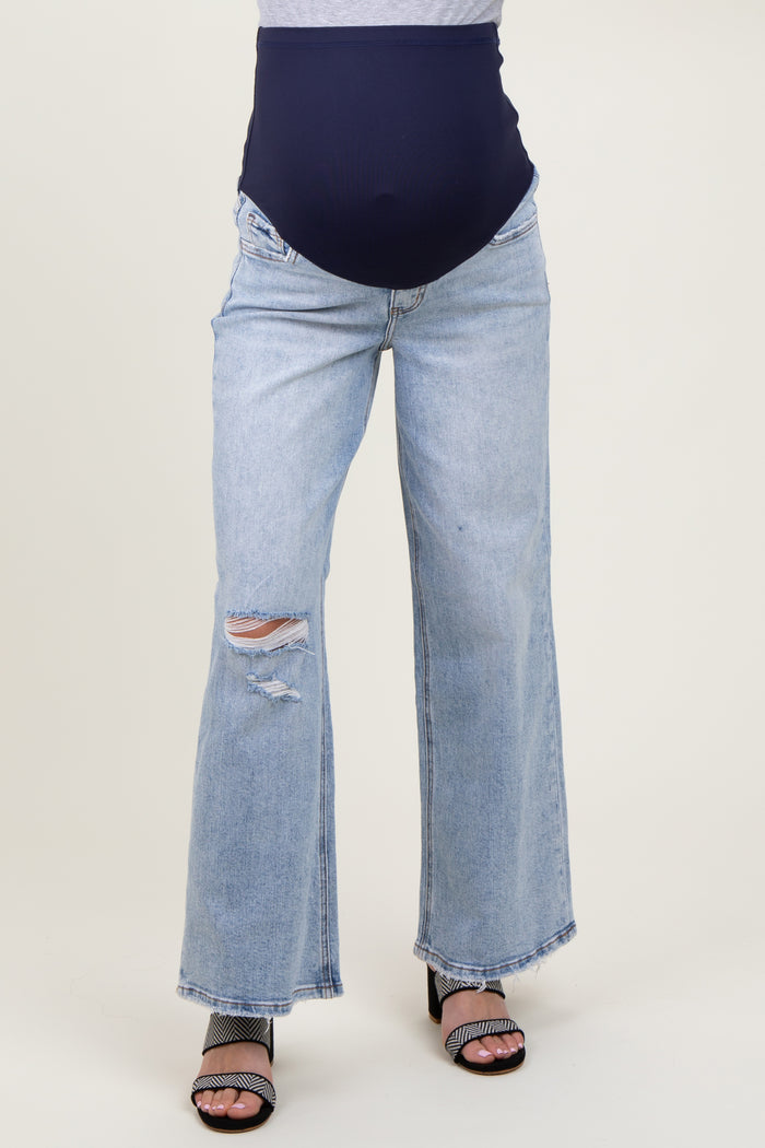 woman wearing light blue distressed maternity jeans with a navy blue over-the-bump waistband