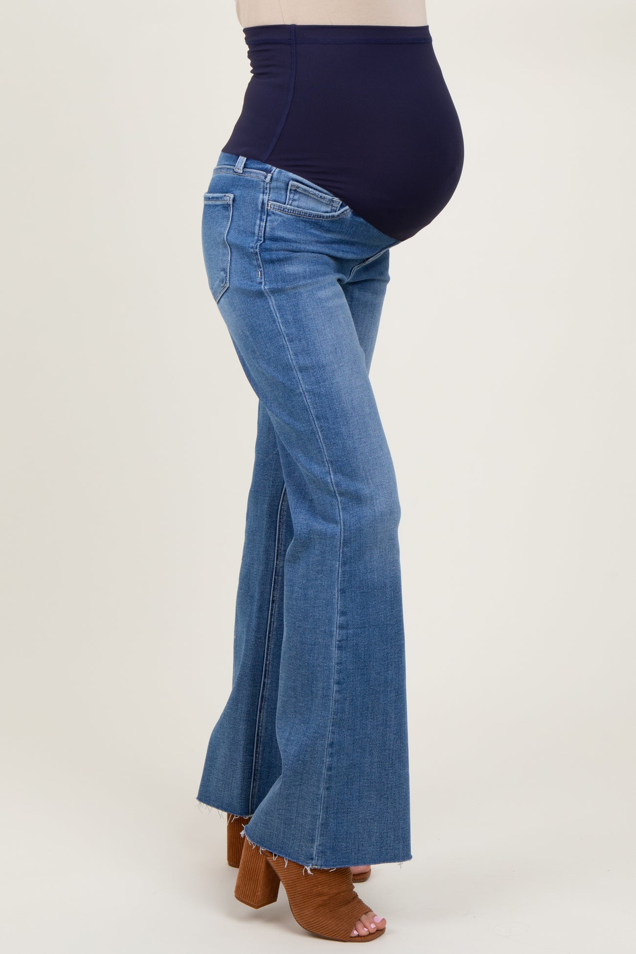 woman wearing dark blue maternity flared jeans with a high waistband and visible baby bump