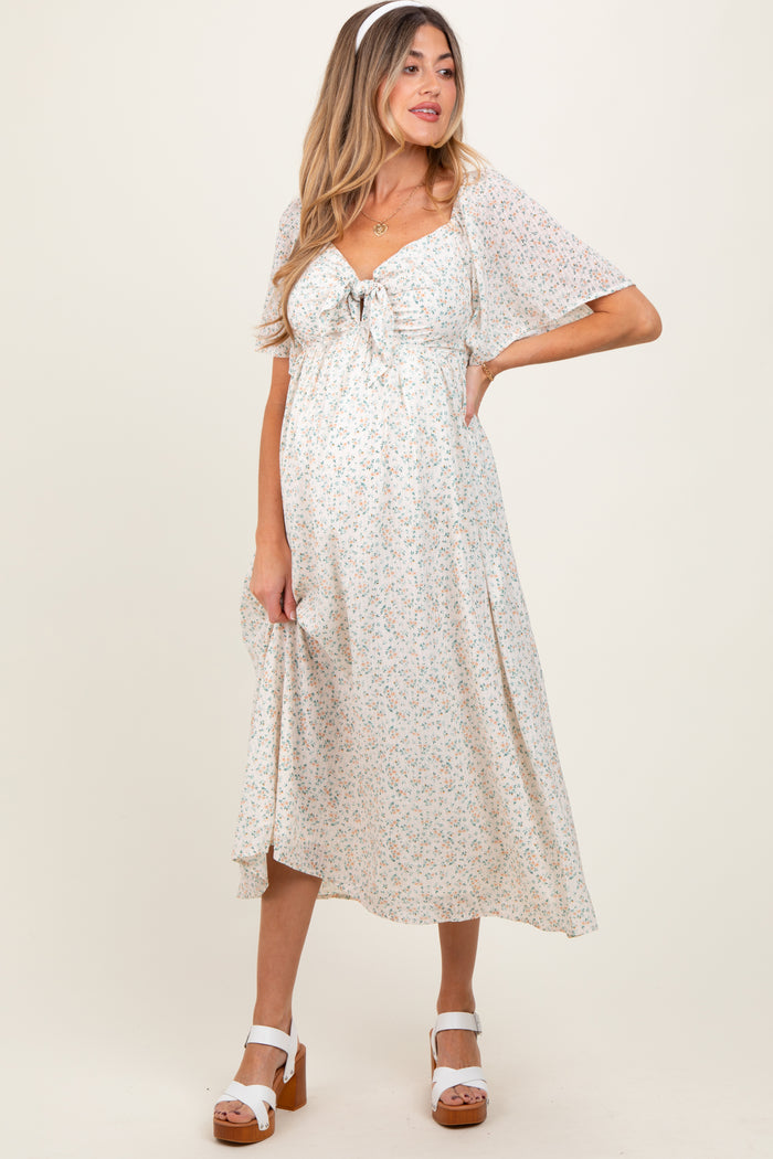 woman wearing a floral maternity dress with a tie front and short sleeves, showcasing her baby bump