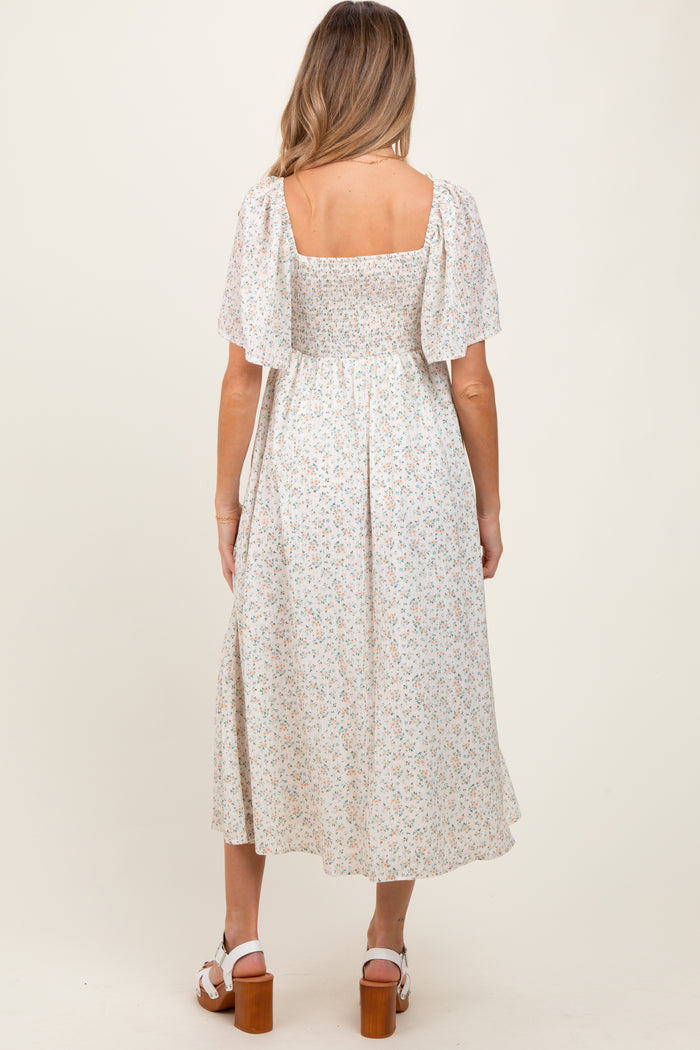 woman wearing a light floral maternity maxi dress with short puff sleeves and a square back
