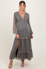 woman wearing a floral maternity maxi dress with long sleeves and a v-neckline, featuring a slit and ruffled tiers