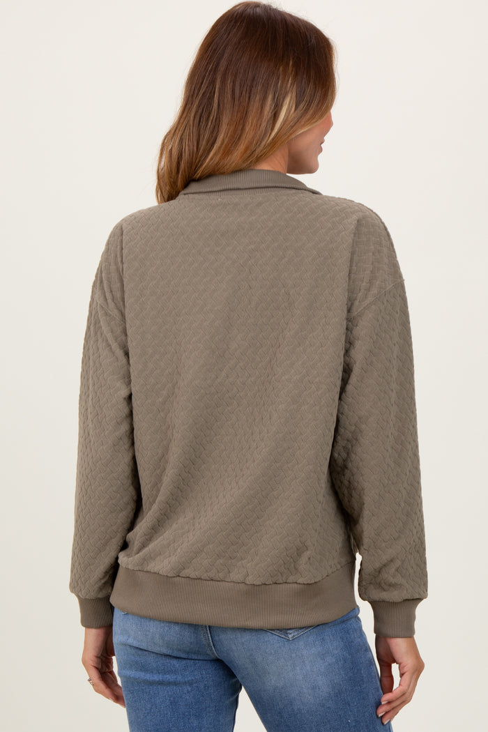 women wearing a khaki quilted pullover sweatshirt with a relaxed fit and ribbed hem