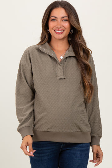 woman wearing a light olive green maternity pullover sweatshirt with a collar and buttons, smiling at the camera