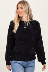 woman wearing a black ribbed pullover sweater with long sleeves and a relaxed fit, paired with denim jeans