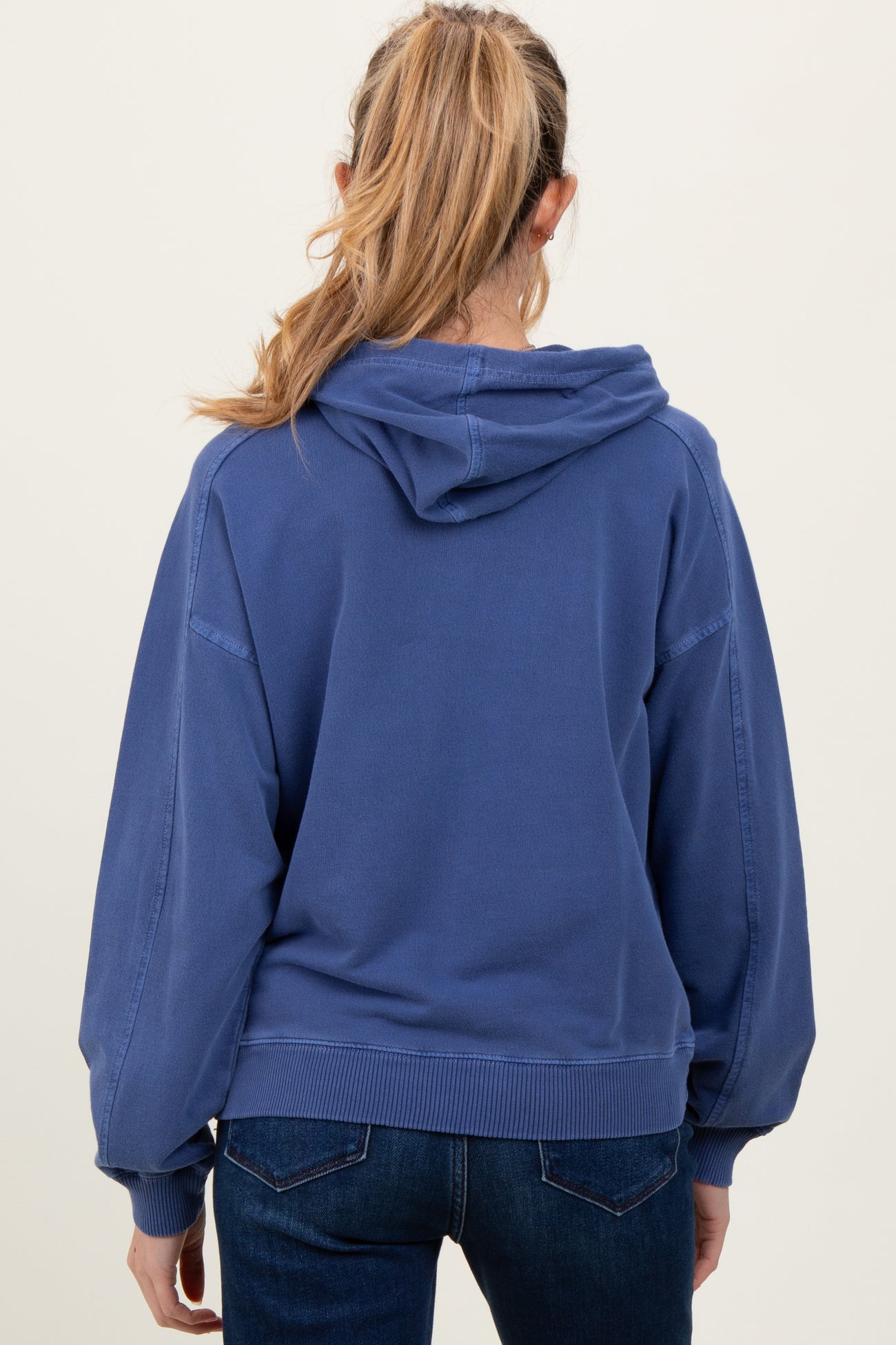 woman wearing a blue maternity hoodie with a relaxed fit and a hood, shown from the back