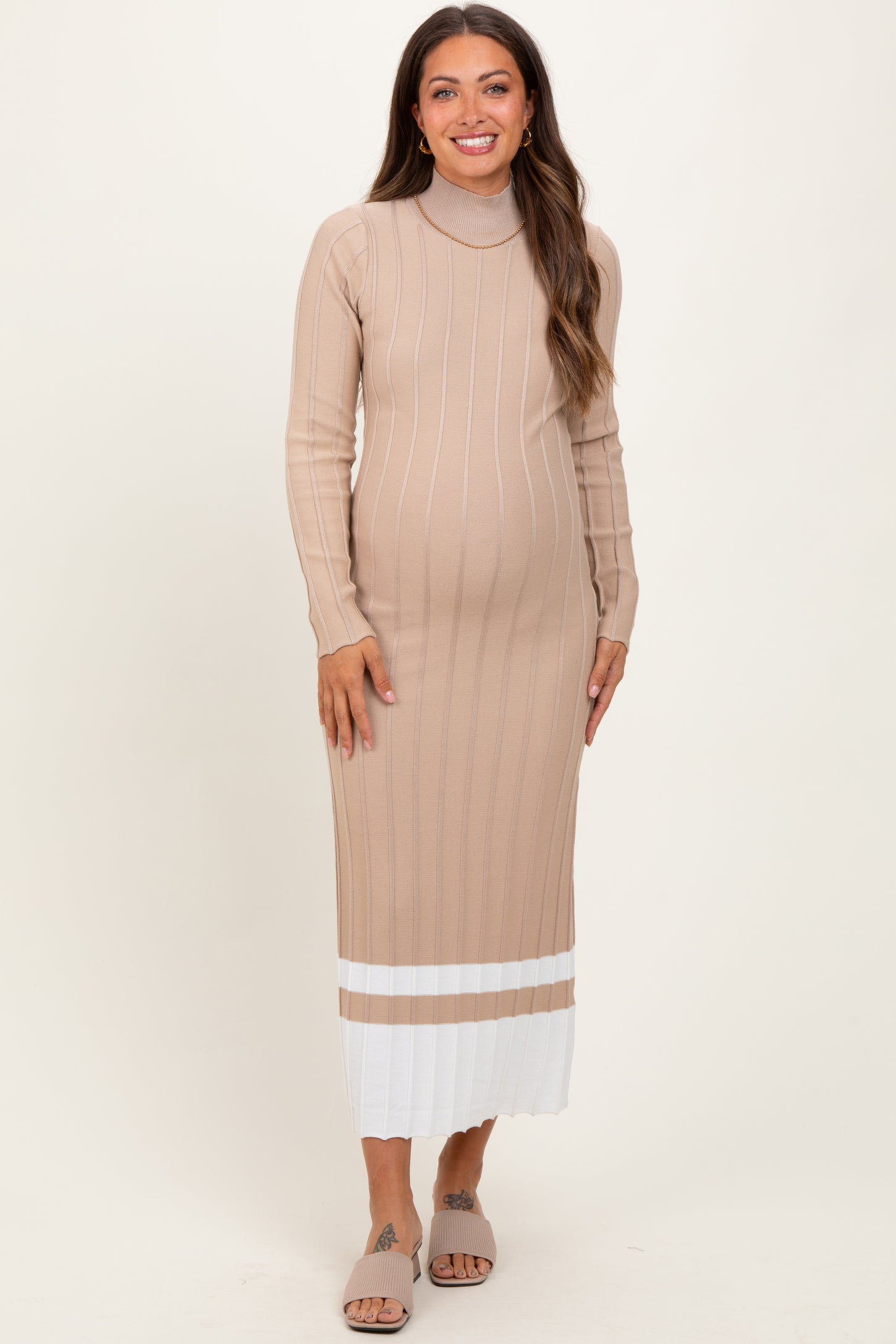 woman wearing a beige maternity dress with long sleeves and a ribbed texture, showing her baby bump