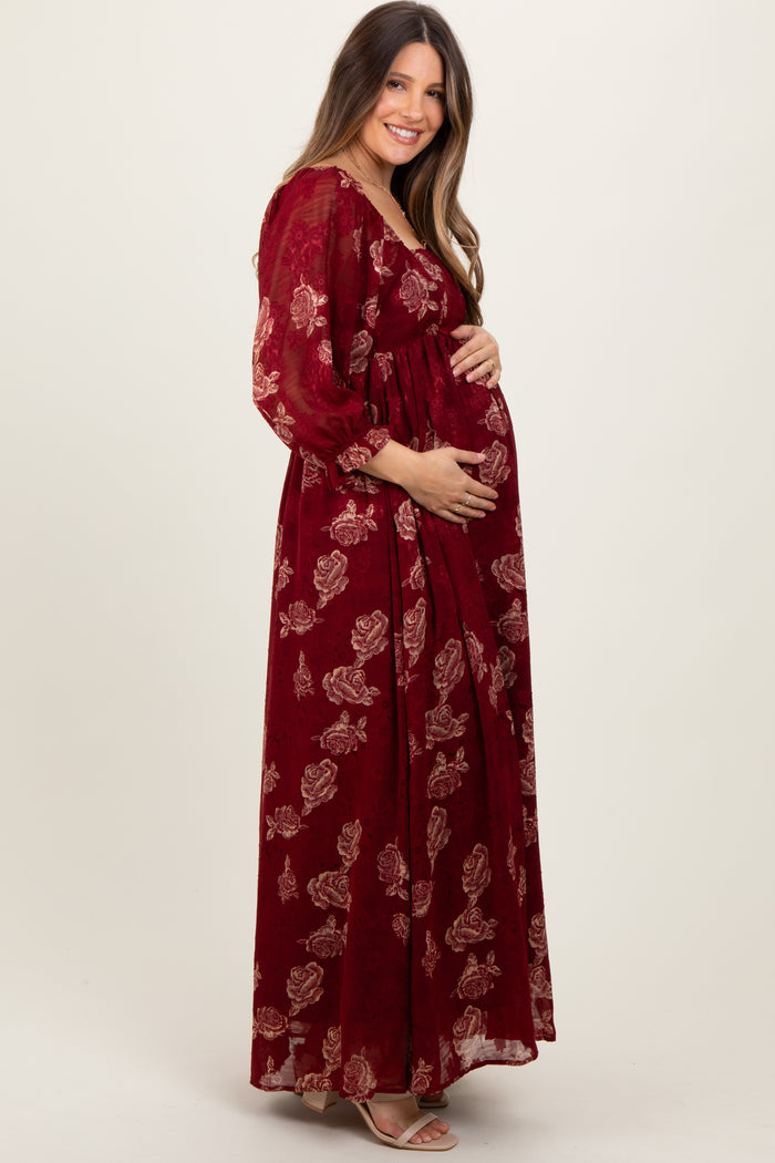 woman wearing a burgundy floral maternity maxi dress and holding her baby bump