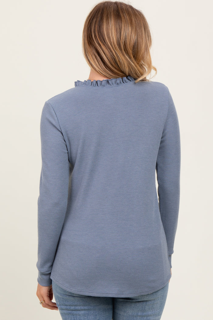 woman wearing a light blue long sleeve top with ruffle neckline and textured fabric, viewed from the back