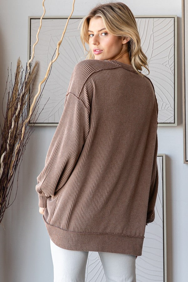 woman wearing a brown ribbed oversized sweater viewed from the back, styled with light-colored pants