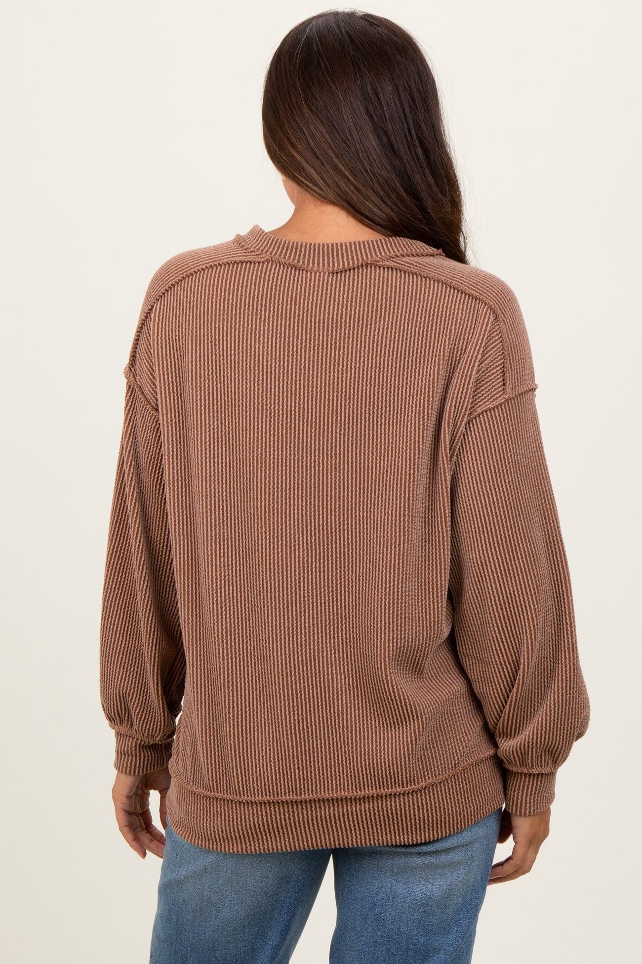 woman wearing a brown ribbed maternity sweater with a loose fit and balloon sleeves, viewed from the back