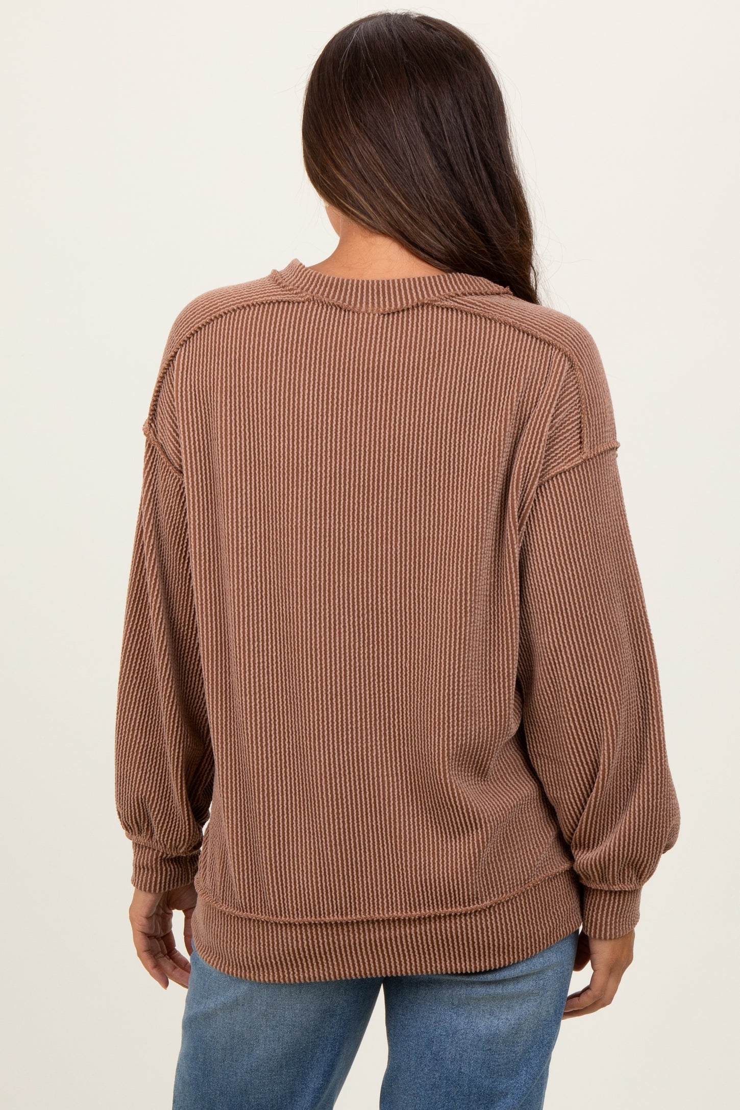woman wearing a brown ribbed maternity sweater with a loose fit and balloon sleeves, viewed from the back