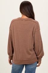 woman wearing a brown ribbed maternity sweater with a loose fit and balloon sleeves, viewed from the back