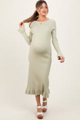 woman wearing a light green ribbed maternity dress with a ruffled hem and a visible baby bump