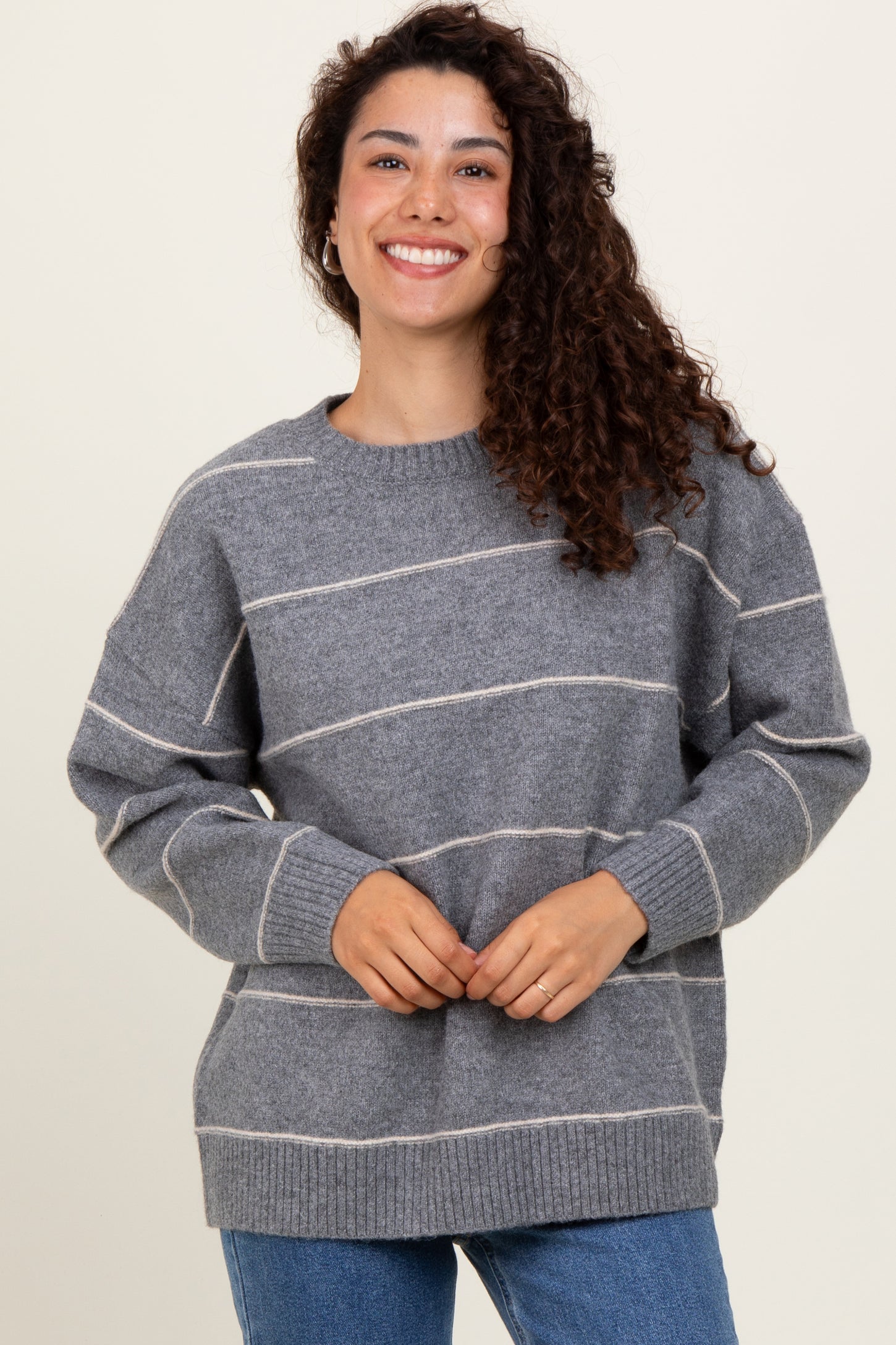 woman wearing a gray striped sweater with a relaxed fit and smiling