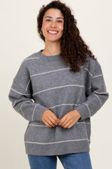 woman wearing a gray striped sweater with a relaxed fit and smiling