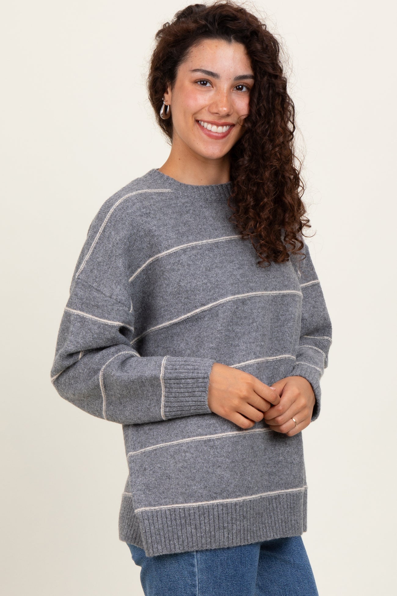 woman wearing a gray striped sweater with a relaxed fit and ribbed cuffs