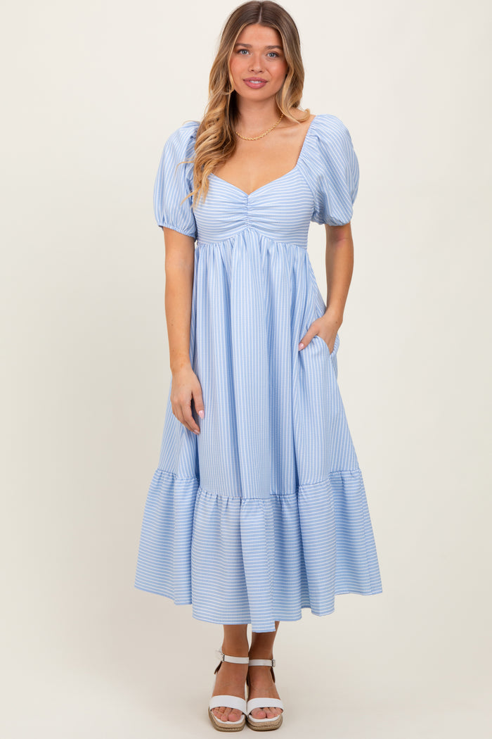 woman wearing a light blue striped puff sleeve midi dress with a tiered hem and pockets