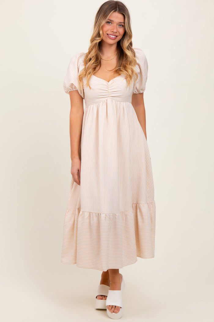 woman wearing a beige and white striped maxi dress with puff sleeves and a ruffled hemline