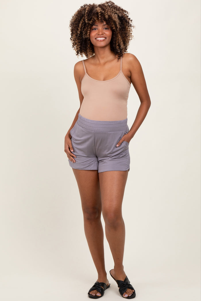 woman wearing a nude tank top and gray maternity shorts with pockets, standing confidently