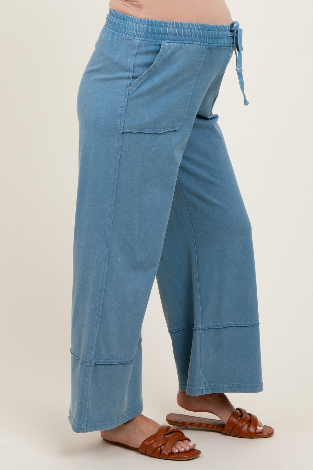 woman wearing light blue maternity wide-leg pants with pockets and a drawstring waistband, showing her baby bump