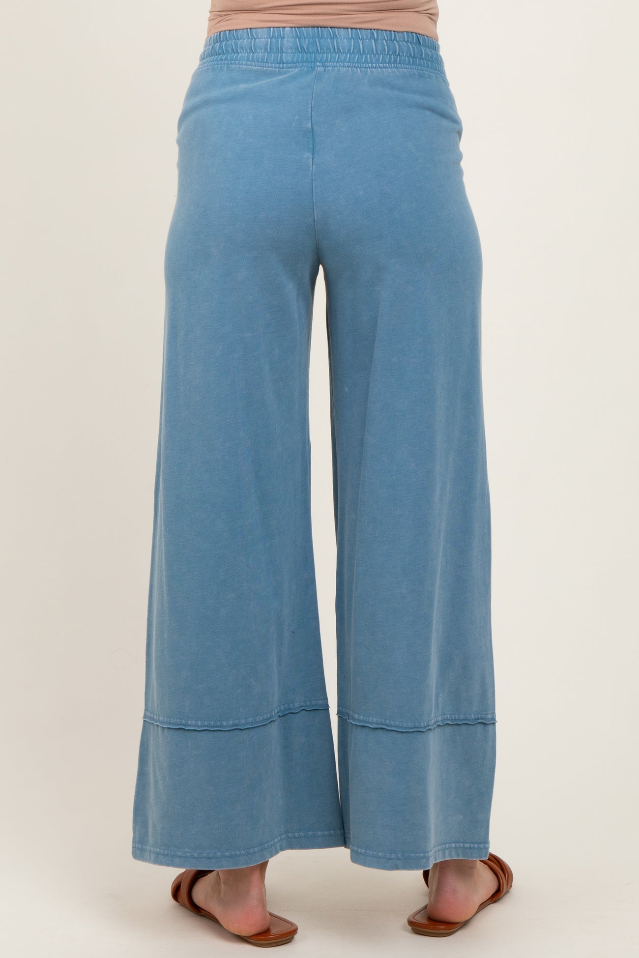 woman wearing light blue maternity wide-leg pants, showing the back view with an elastic waistband