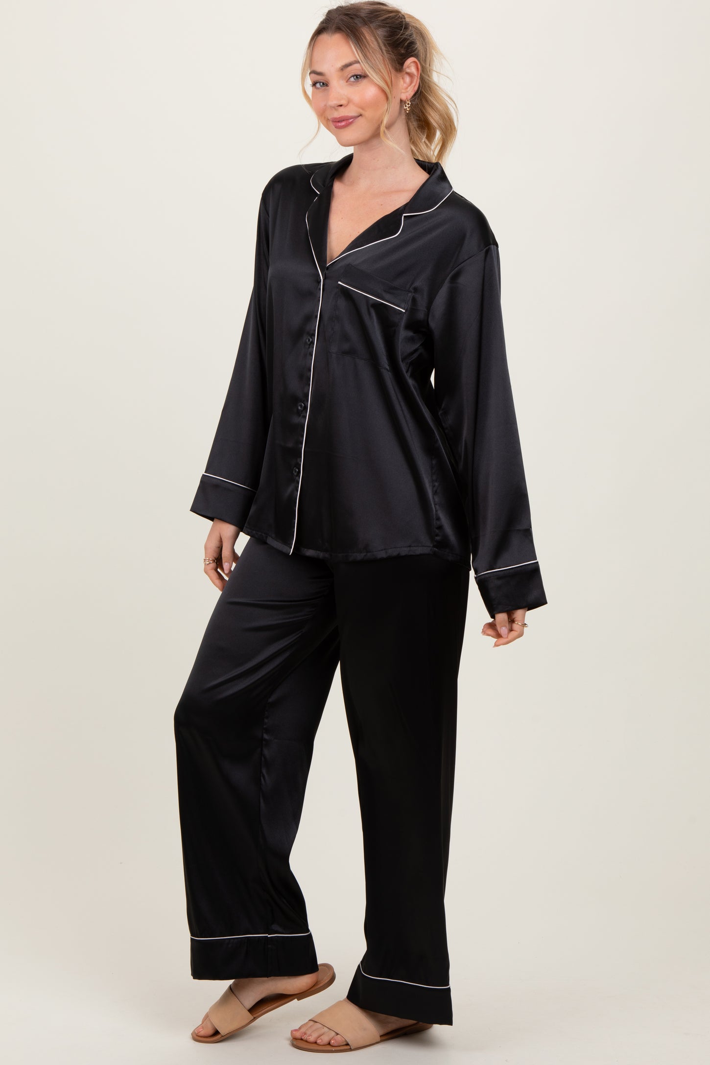 woman wearing a black satin long sleeve pajama set with white piping details